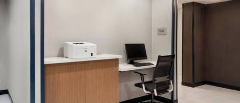 Un mostrador de recepción con una impresora, computadora y una silla de oficina en un espacio de trabajo moderno.