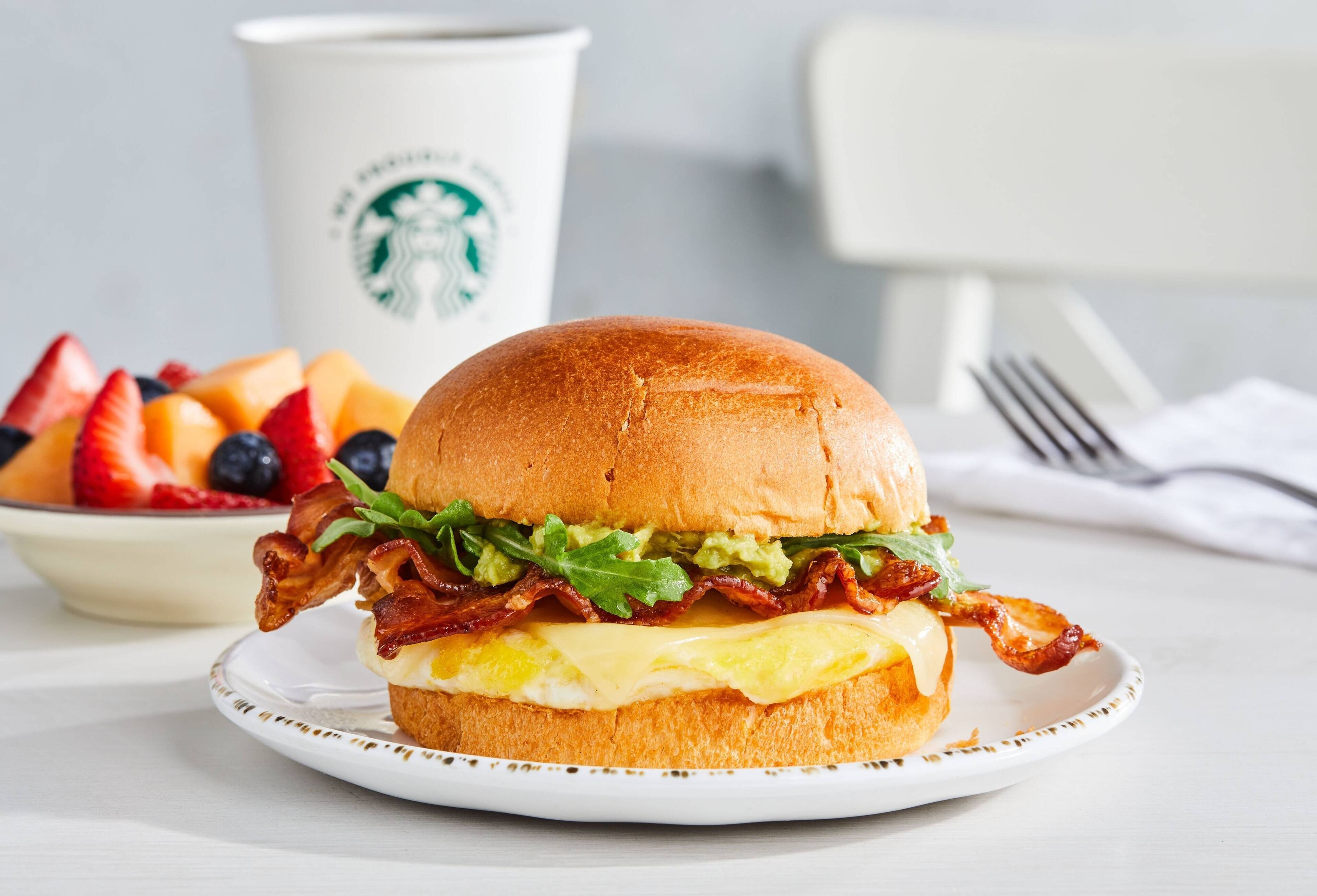 Een belegd boterham op een bord, met een Starbucks-beker op de achtergrond.