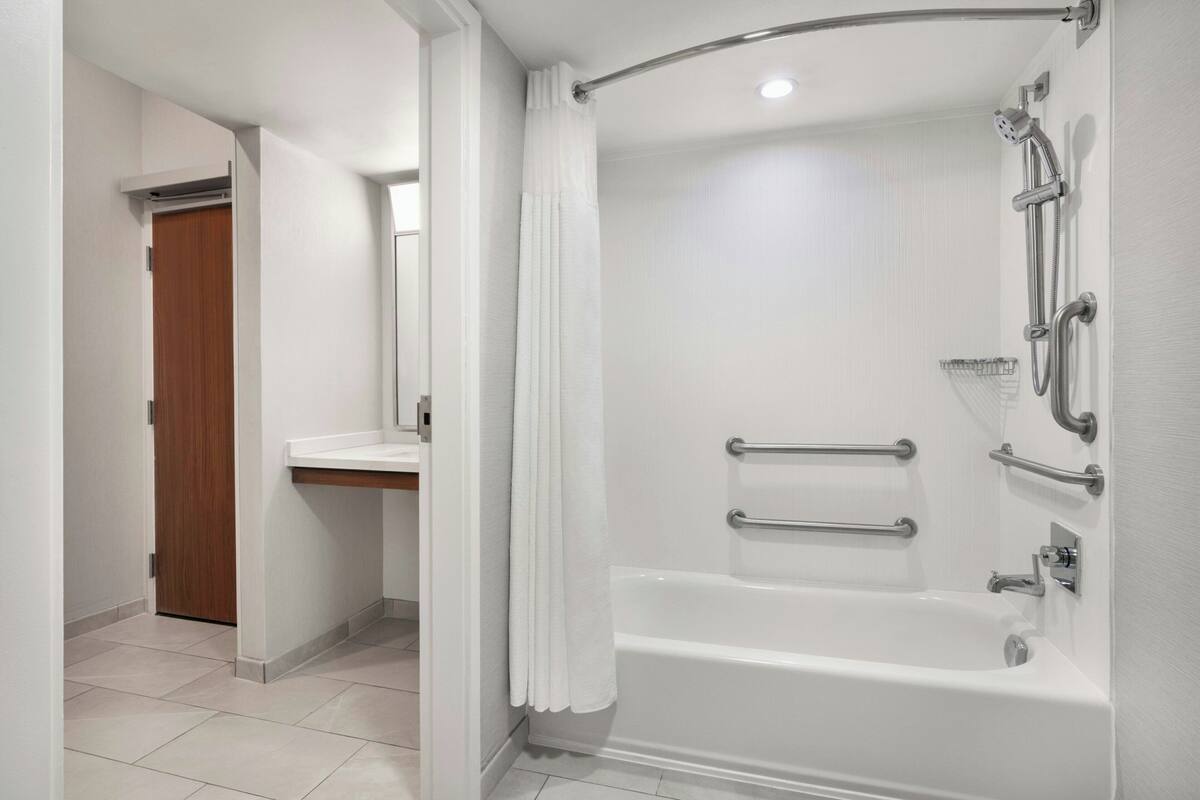 A modern bathroom with a walk-in shower, grab bars, and a separate bathtub.