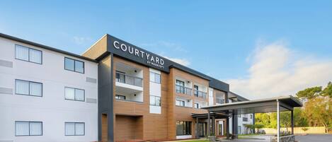 A Courtyard by Marriott hotel with a modern design, a covered entrance, and a parking lot.