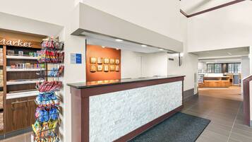 A hotel reception area with a white reception desk, a market sign, and a wall with framed pictures.
