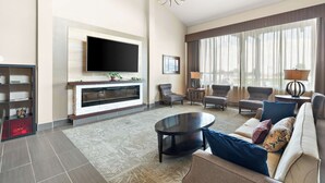 Una sala de estar moderna con televisor de pantalla plana, chimenea, asientos cómodos y ventanas amplias.