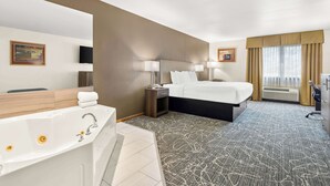 Habitación de hotel con una cama grande, baño privado con bañera, escritorio y ventana con cortinas.