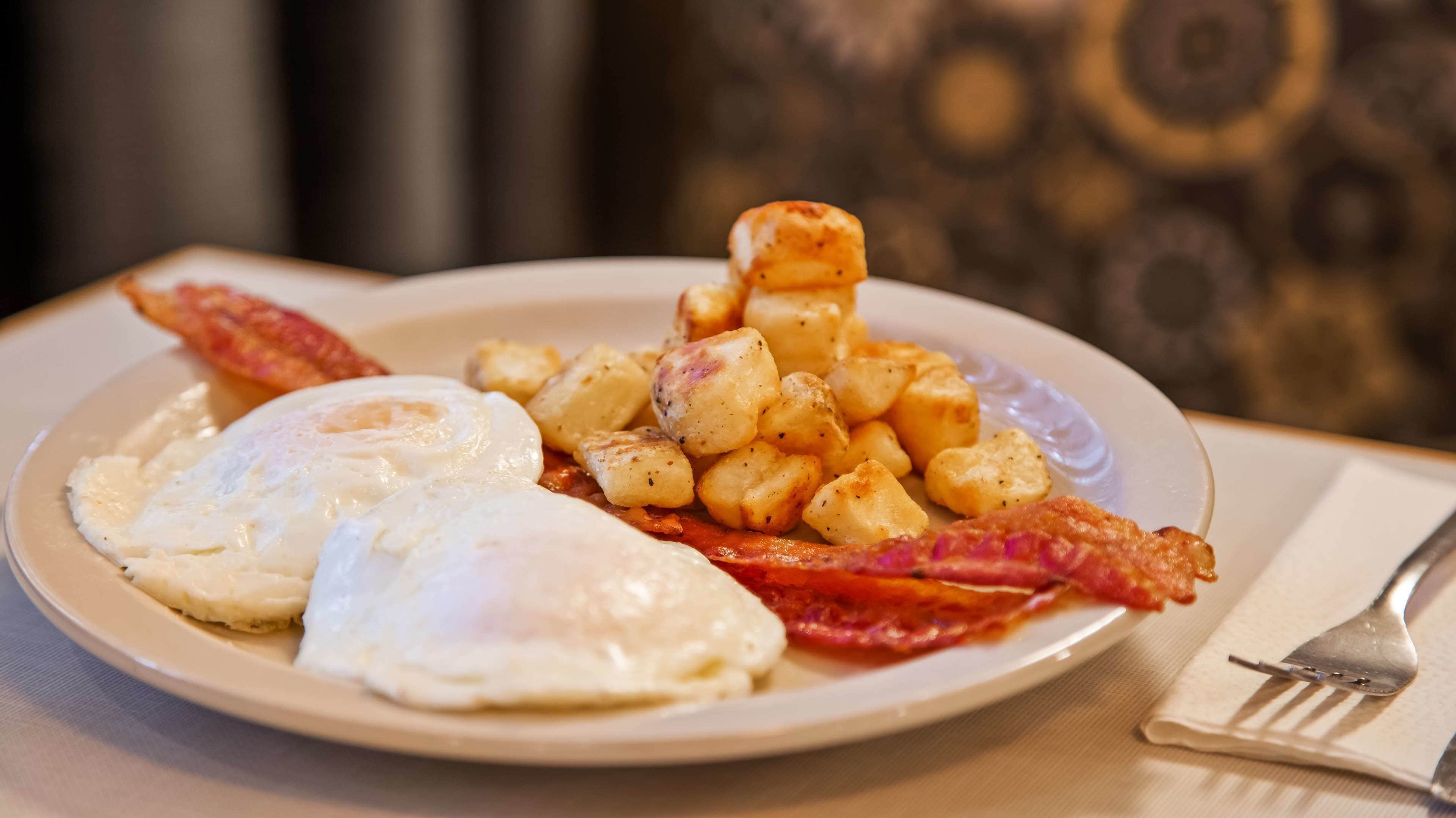 Un plat amb aliments per esmorzar, com ara ous, bacon i patates.
