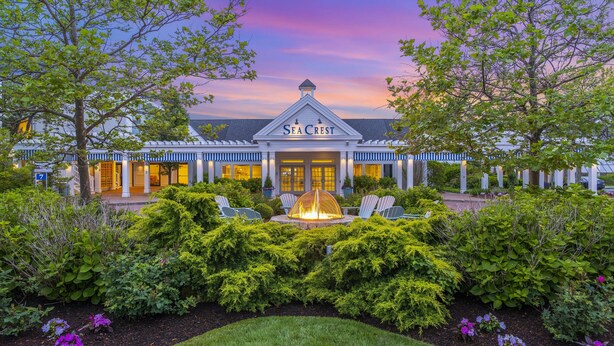 A hotel with a well-maintained garden, a central fire feature, and a sign reading "Sea Crest".