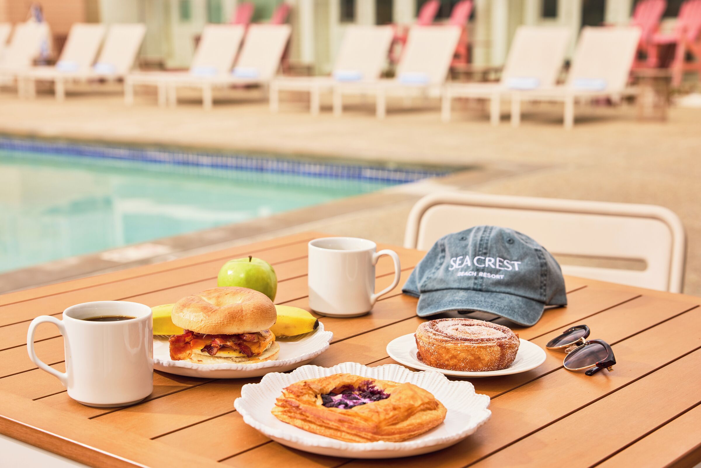 A table with breakfast items including a sandwich, a muffin, a coffee cup, and a cap.