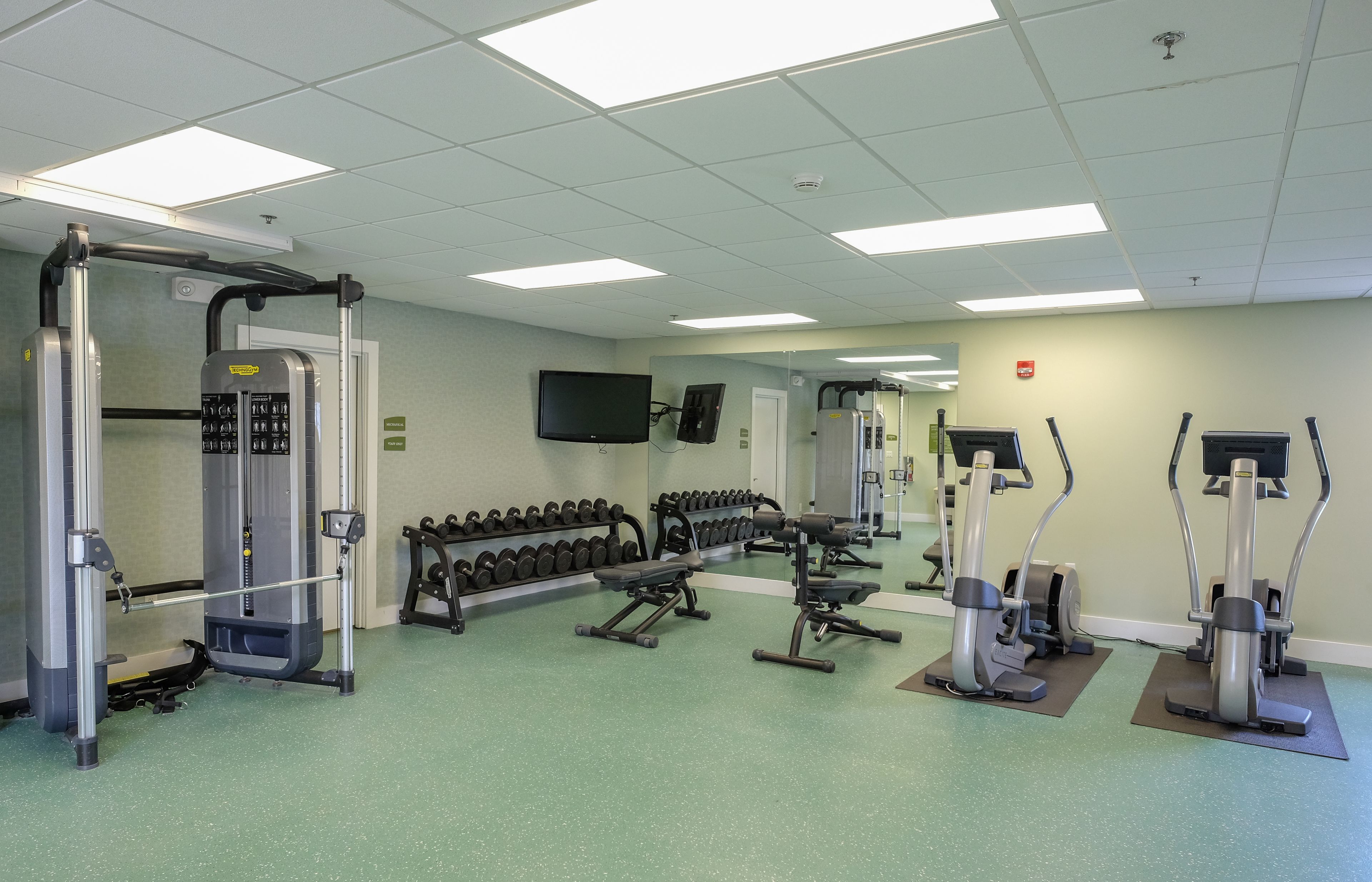 Une salle de sport équipée de divers appareils d’entraînement, notamment des appareils de musculation, des haltères et des appareils de cardio.