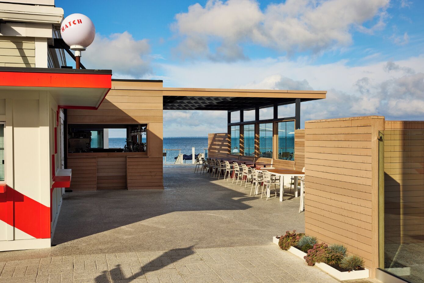 A coastal restaurant with outdoor seating, a bar, and a view of the sea.