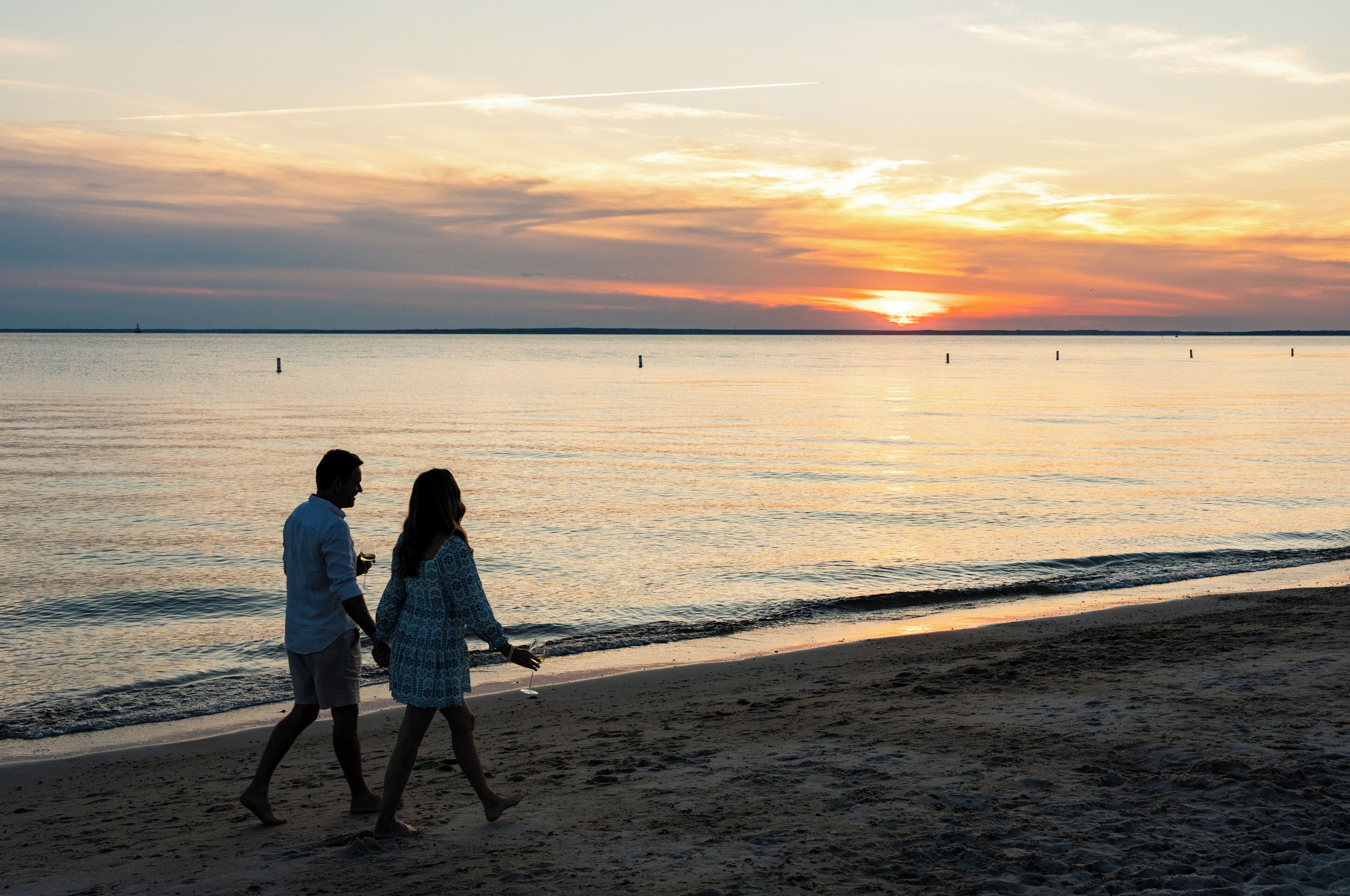 Una pareja caminando por la playa al atardecer.