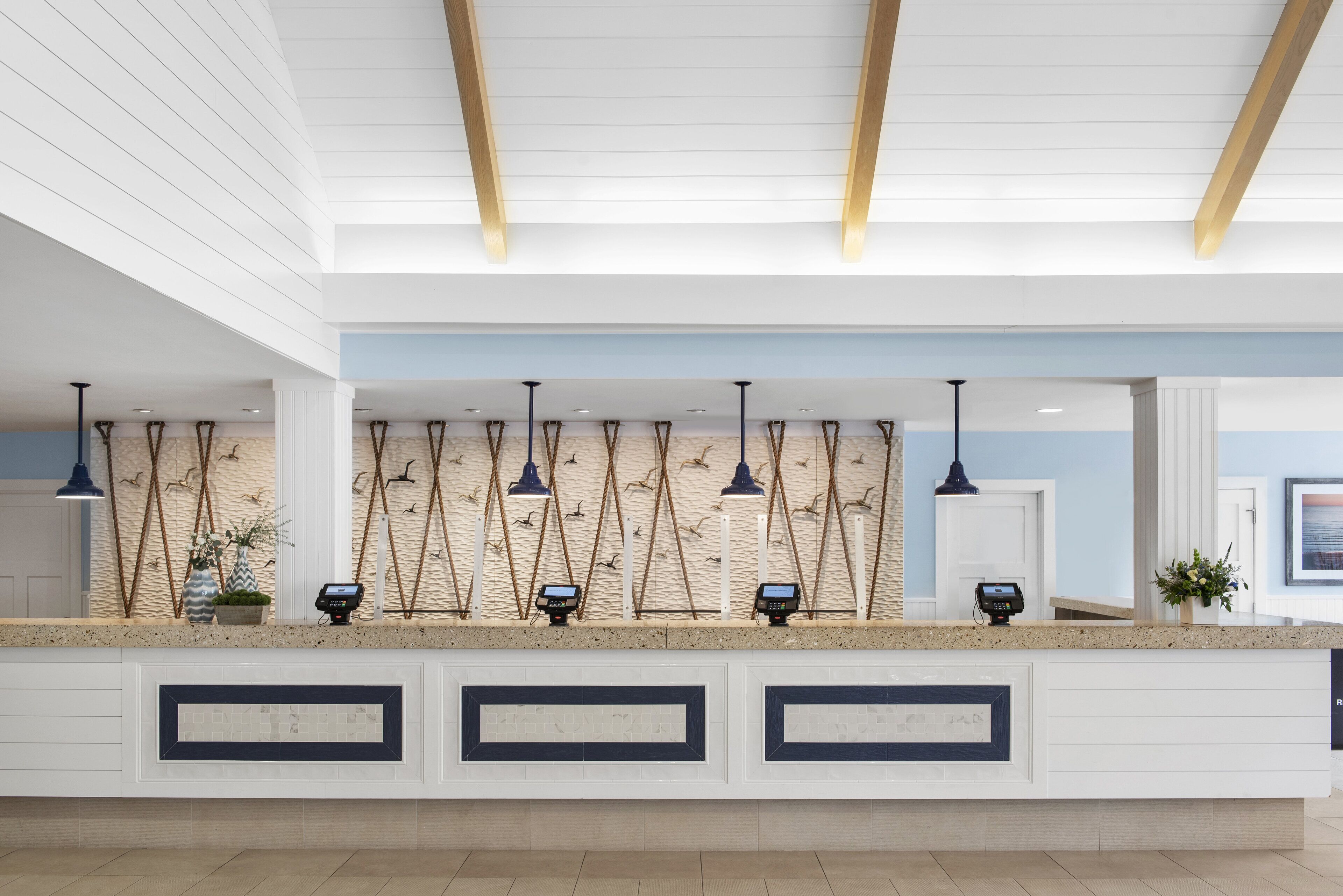 A reception area with a counter, pendant lights, and a wall with decorative elements.