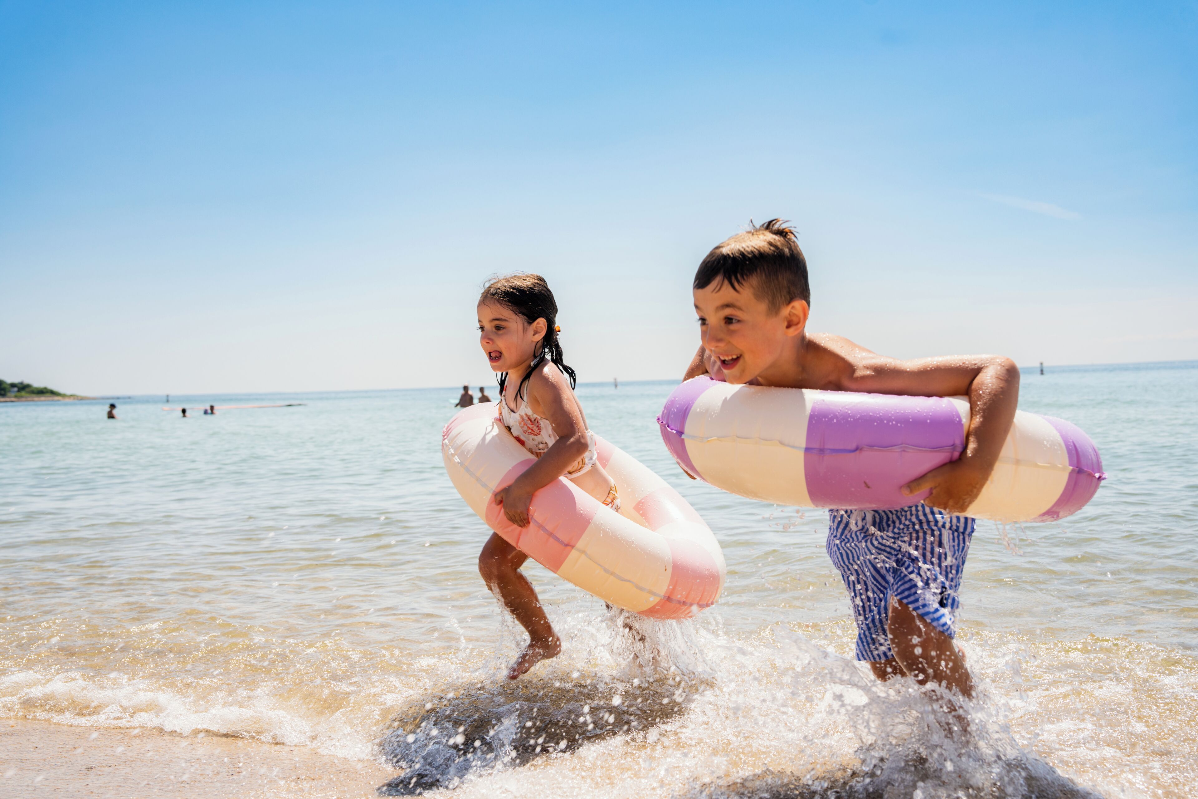Two children playing in the water with inflatable rings.