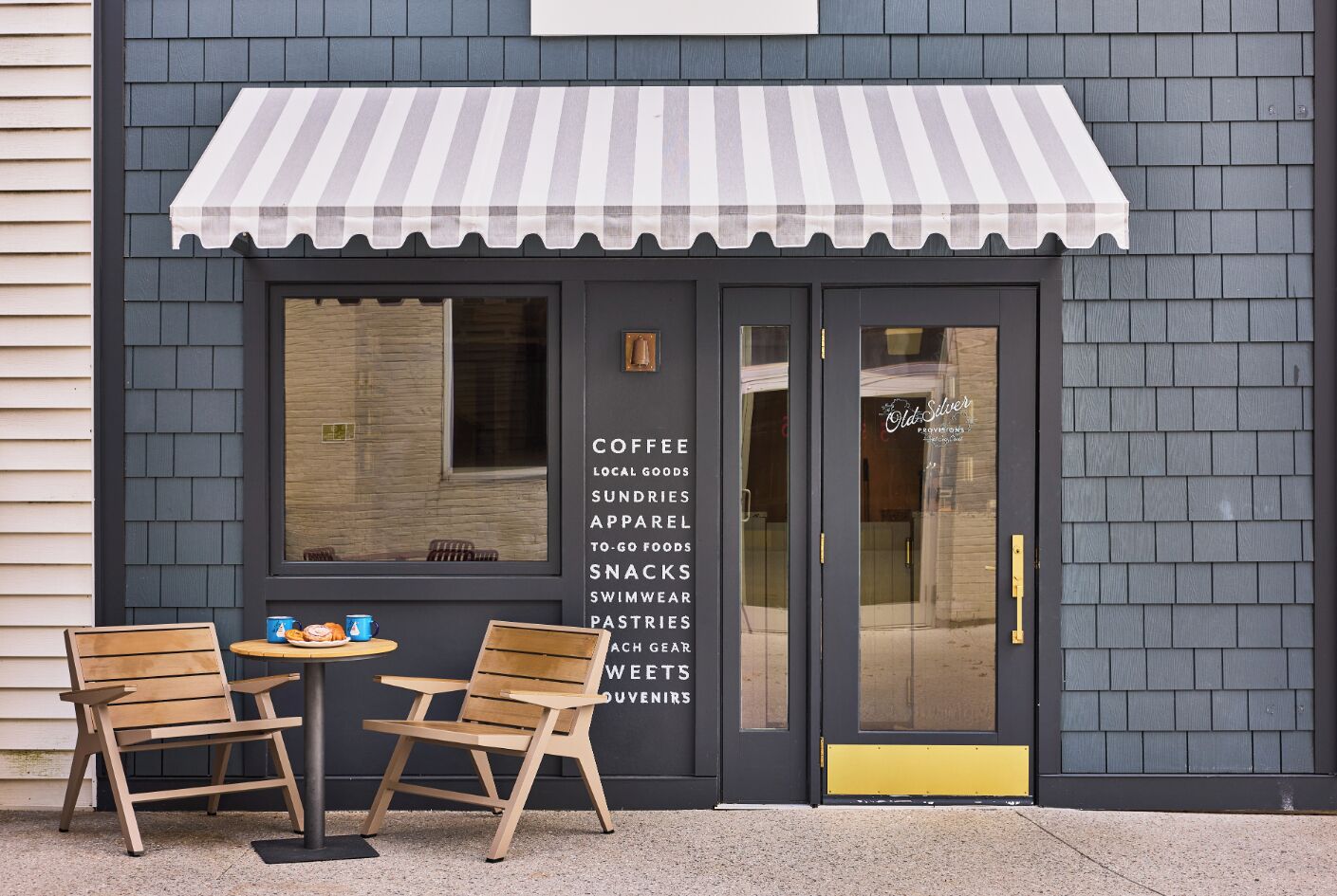 A storefront with a striped awning and a list of offerings including coffee, local goods, and snacks.
