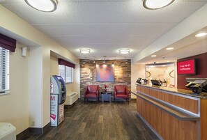 A reception area with a stone wall, two red chairs, a reception desk, and an ATM.