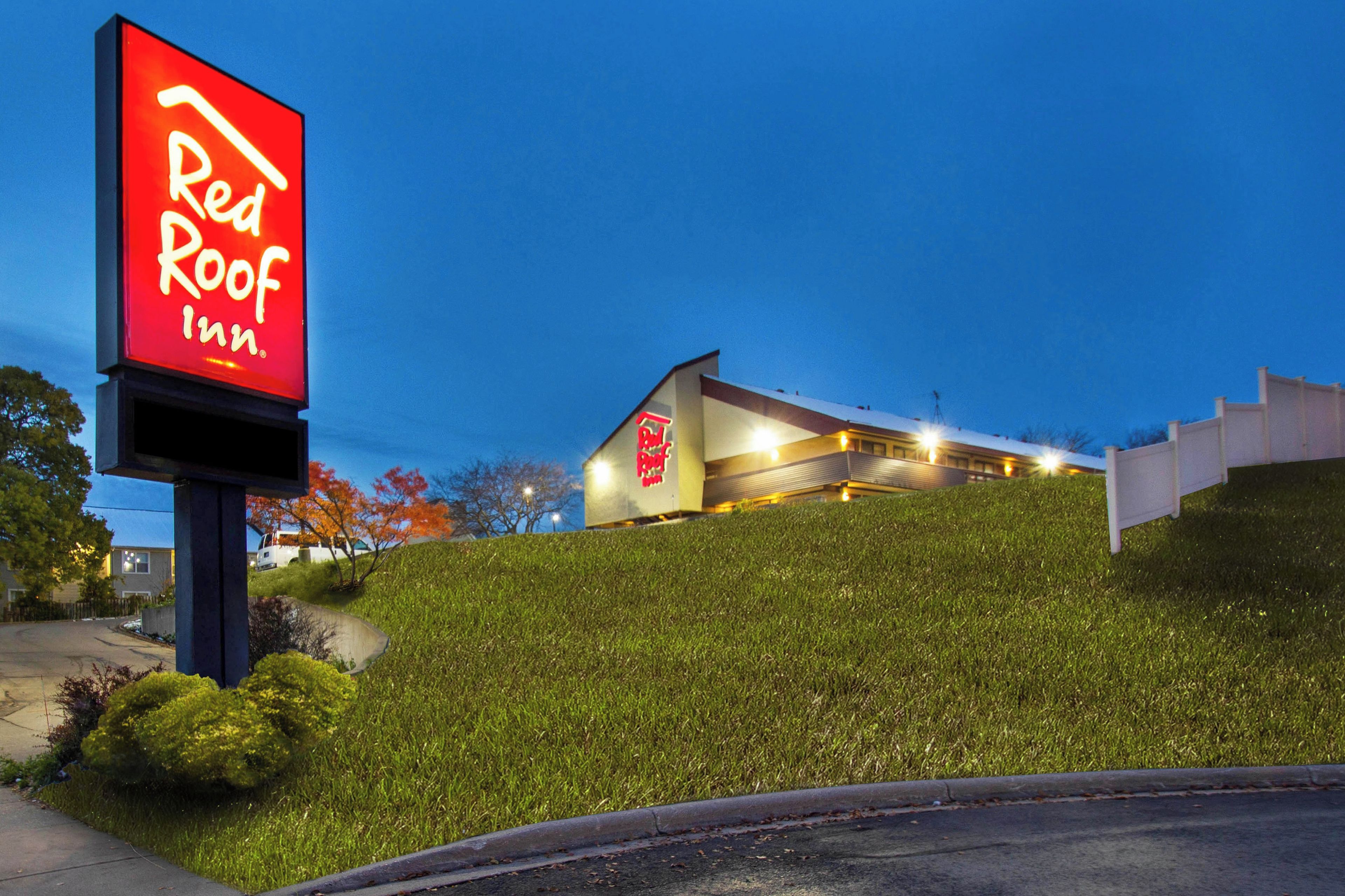 A Red Roof Inn with a modern building and a large illuminated sign.