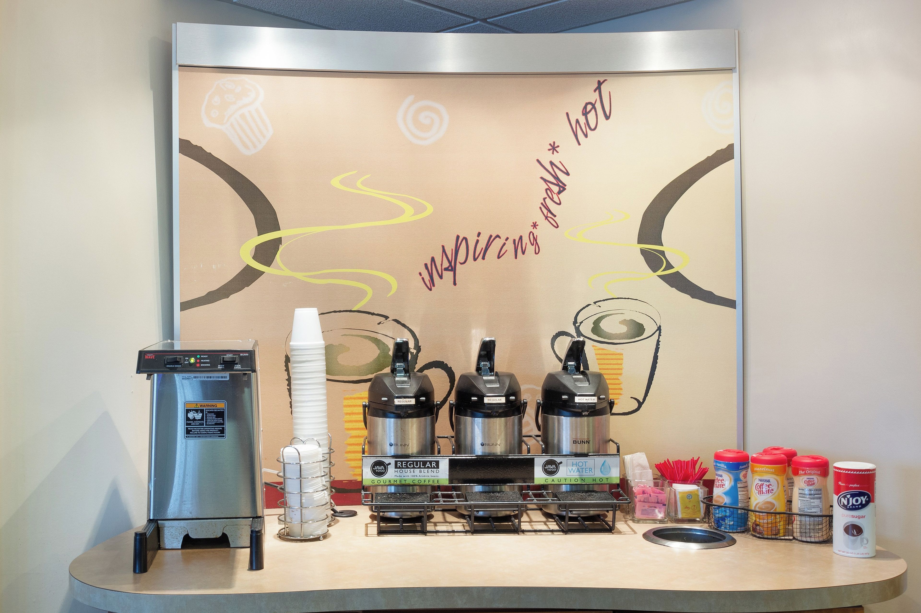 A coffee station with a coffee machine, two hot water dispensers, and various coffee-related items.