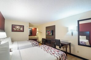A hotel room with two beds, a desk, a chair, a television, and a mirror.