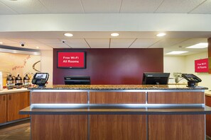 A reception desk with a flat-screen TV displaying 'Free Wi-Fi All Rooms' and a Lenovo computer. - Red Roof Inn Madison, WI (Madison)