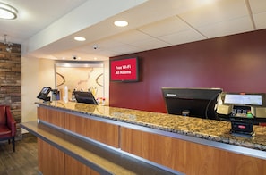 A hotel reception area with a digital screen displaying 'Free Wi-Fi All Rooms,' a coffee machine, and a payment terminal. - Red Roof Inn Madison, WI (Madison)
