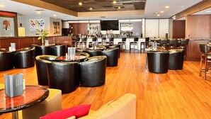 A modern bar area with leather seating, a bar counter, and a television screen. - Wyndham Garden Warsaw (Warsaw)