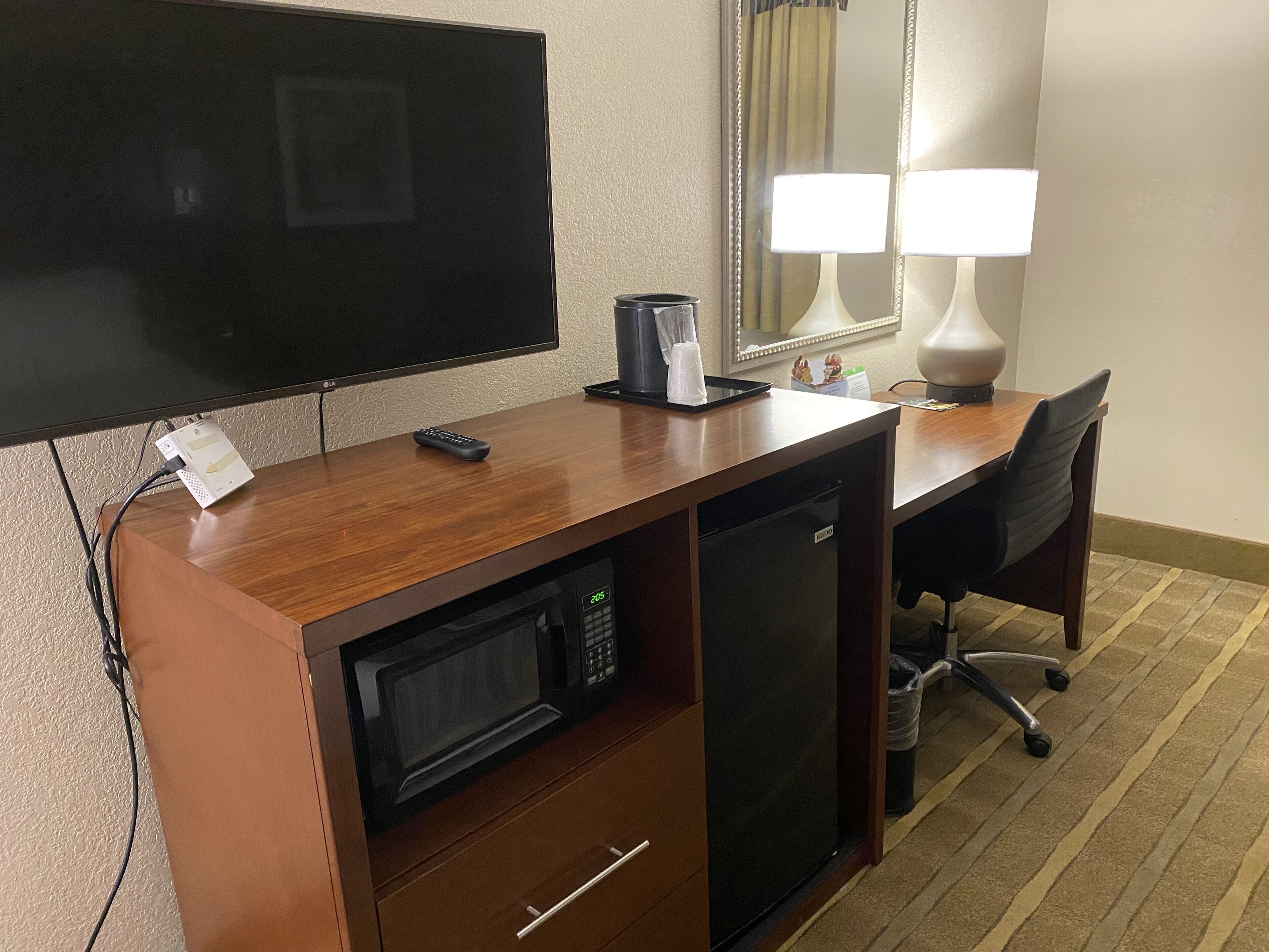 Una kitchenette compacta con microondas, un refrigerador pequeño, cafetera y televisor.