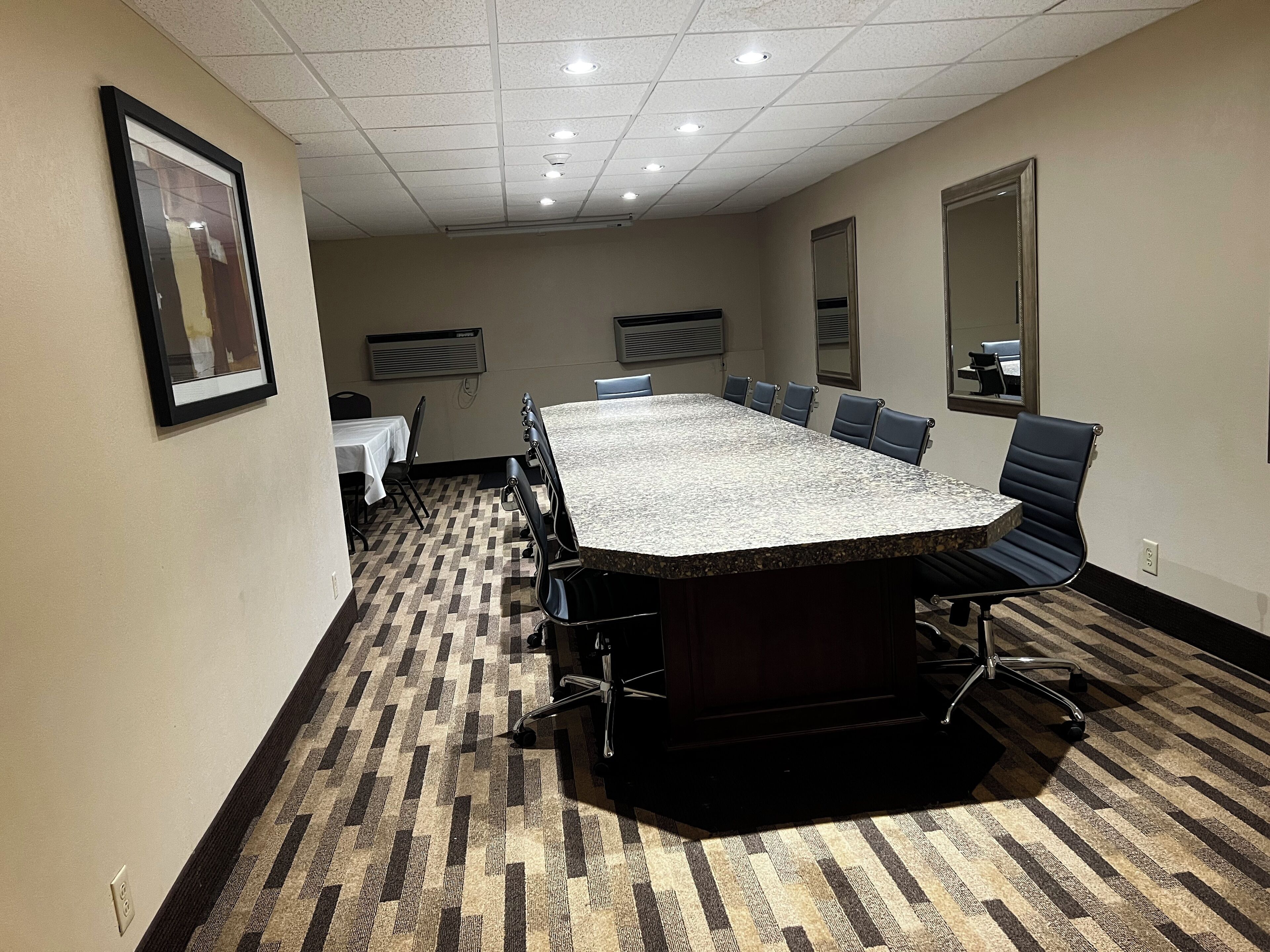Un salón de conferencias con una gran mesa, sillas y piso alfombrado.