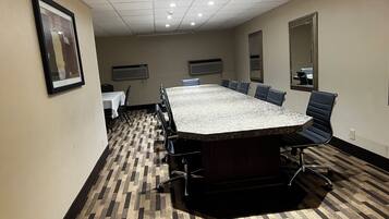 Un salón de conferencias con una gran mesa, sillas y piso alfombrado.