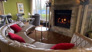 A living room with a stone fireplace, leather sofa, and a small round table. - Wyndham Garden Warsaw (Warsaw)