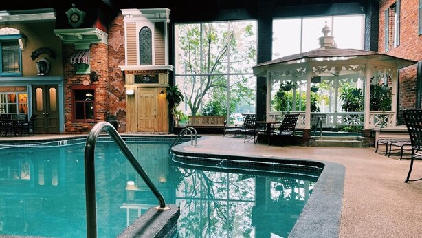 An indoor swimming pool with a clear view of the surrounding area, including a gazebo and a brick building with a sign. - Wyndham Garden Warsaw (Warsaw)