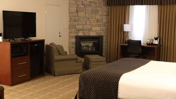 A hotel room with a bed, a television, a fireplace, a desk, and a chair.