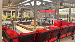 An outdoor patio with a covered seating area, tables, and a fire pit. - Wyndham Garden Warsaw (Warsaw)