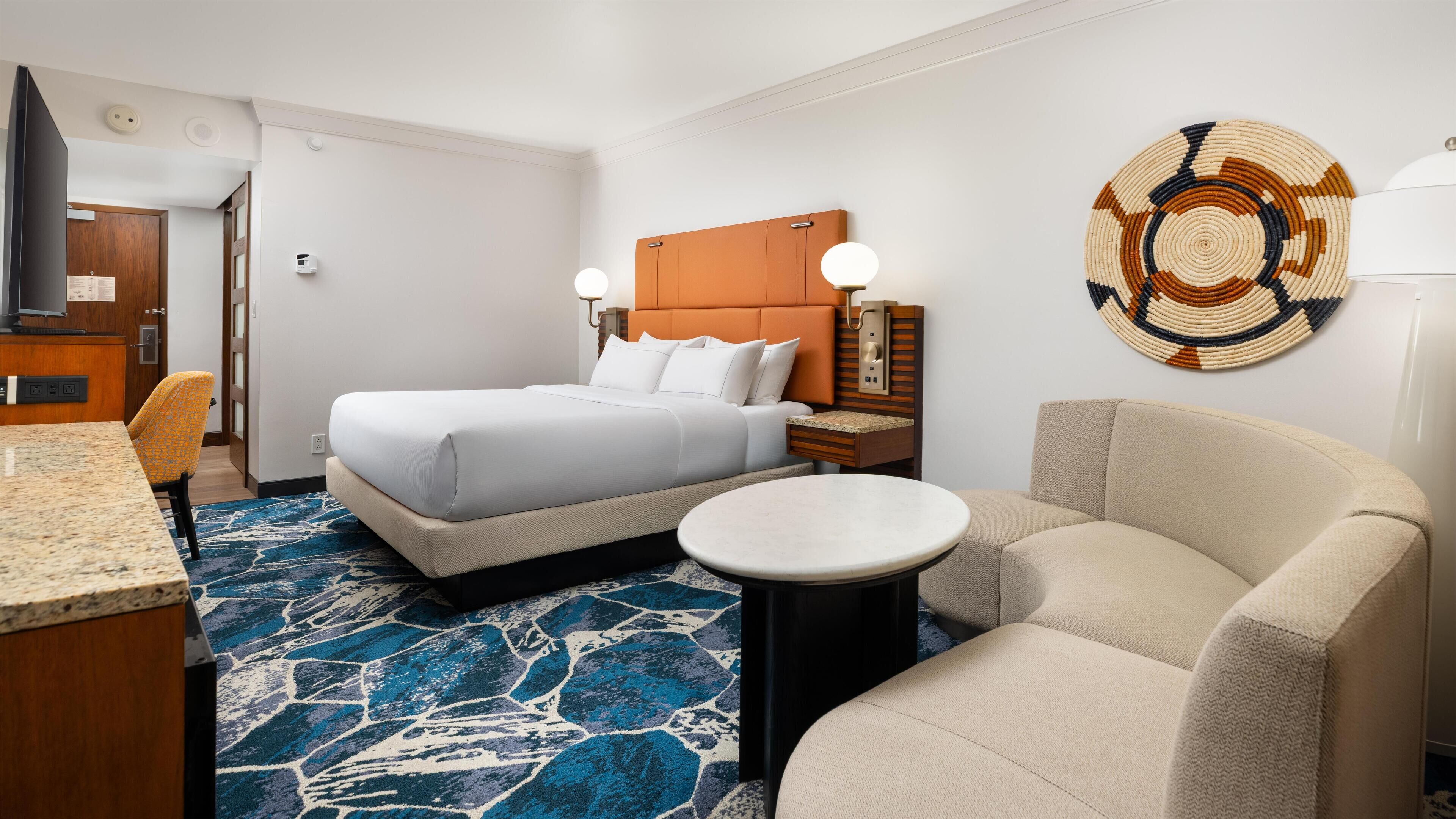 Een hotelkamer met een bed, een ronde tafel, een bank en een decoratieve wandversiering.