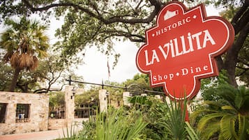 Un panneau historique indiquant l’emplacement de La Villita Shop & Dine, entouré d’une végétation luxuriante.