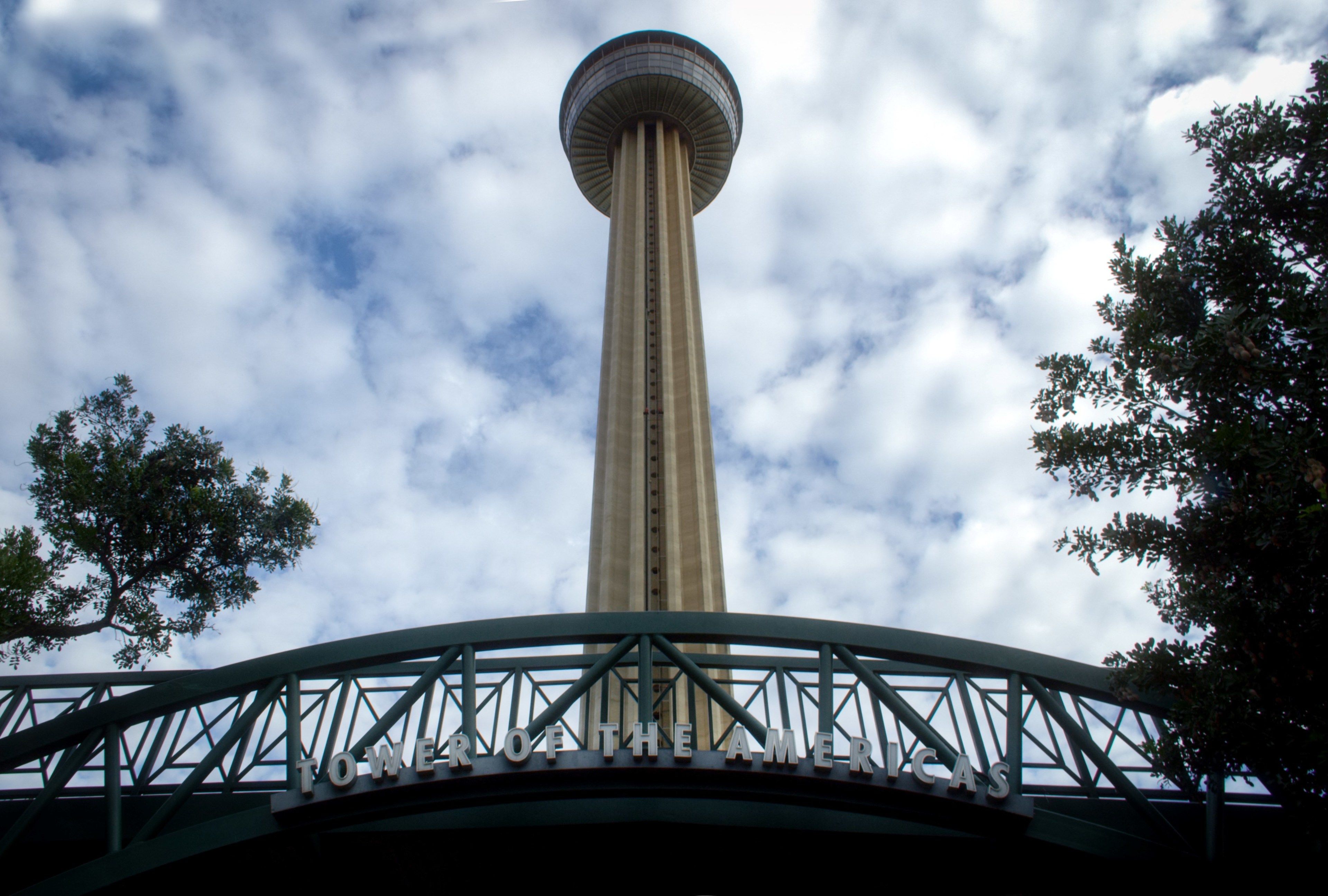 Una torre con un mirador circular, rodeada por un puente metálico con un cartel que dice "TOWER OF THE AMERICAS".