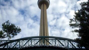 Una torre con un mirador circular, rodeada por un puente metálico con un cartel que dice "TOWER OF THE AMERICAS".