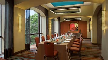 A conference room with a long table, chairs, and a large window with a view.