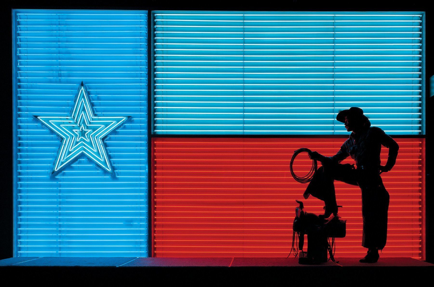 A stage with a blue and red backdrop, a star-shaped neon sign, and a silhouette of a person with a guitar.