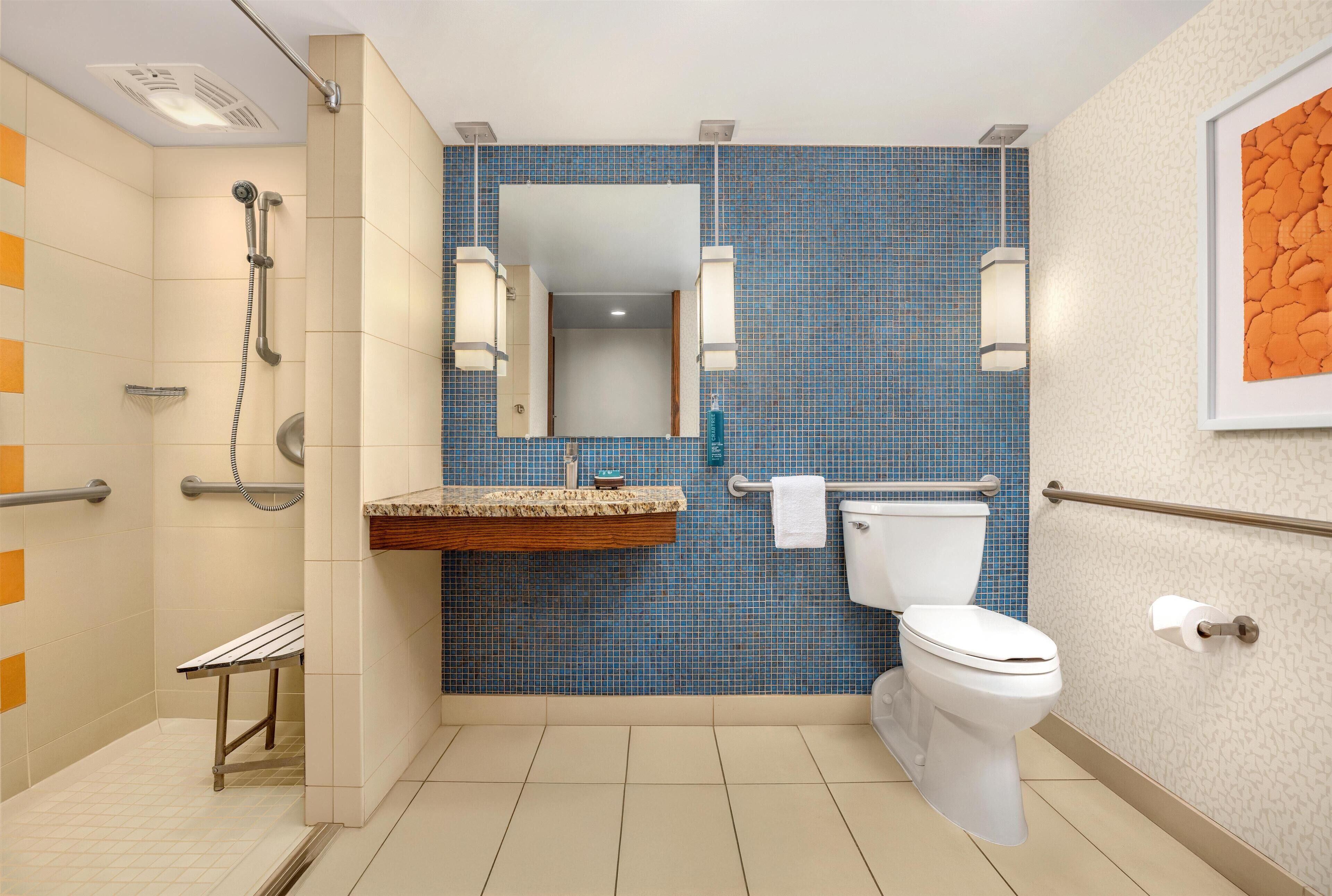 Een badkamer met douche, toilet, wastafel en spiegel.