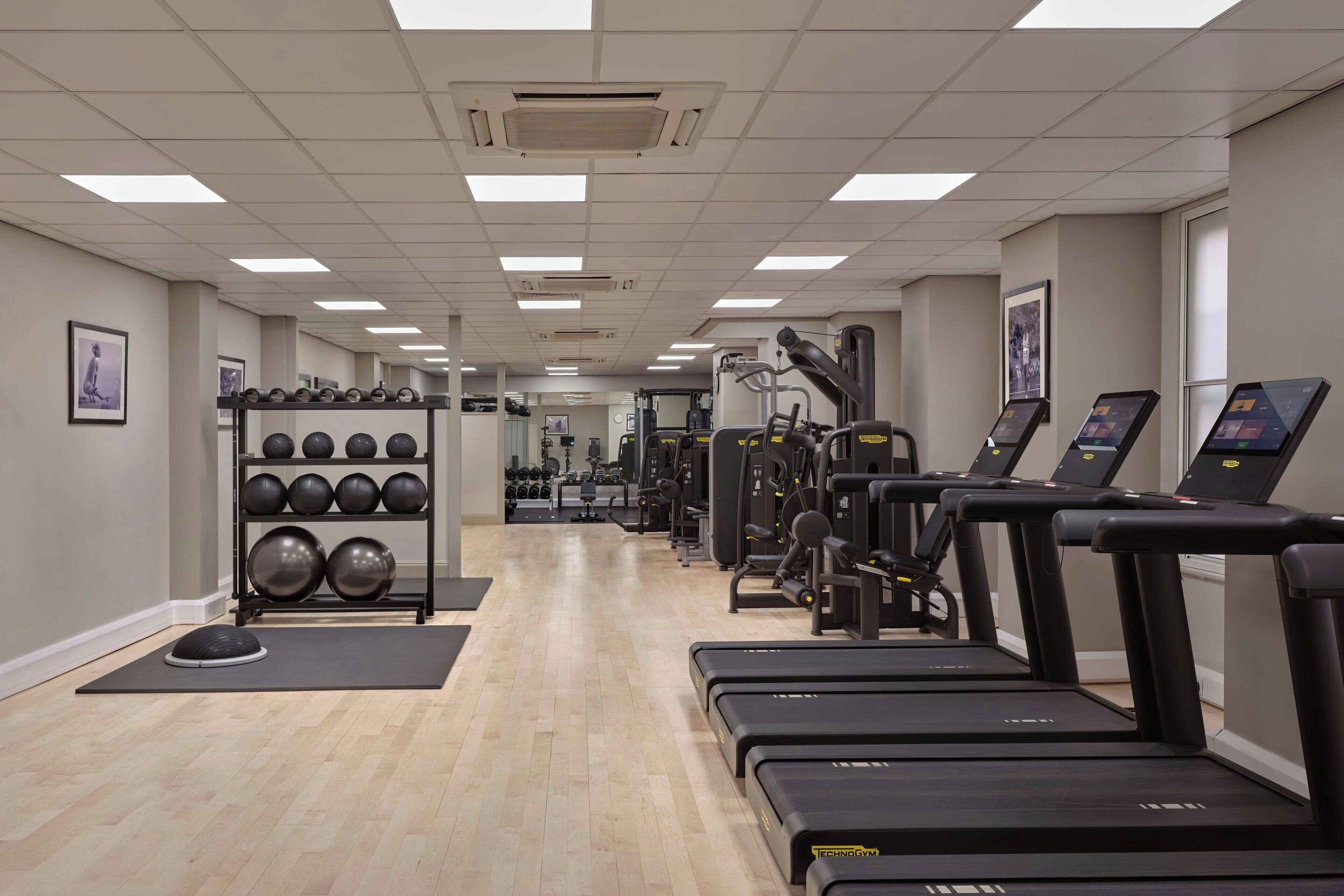 A gym with treadmills, weight machines, and a rack of medicine balls.