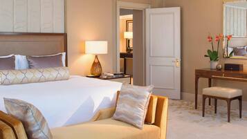 A hotel room with a large bed, a sofa, a desk, and a mirror.