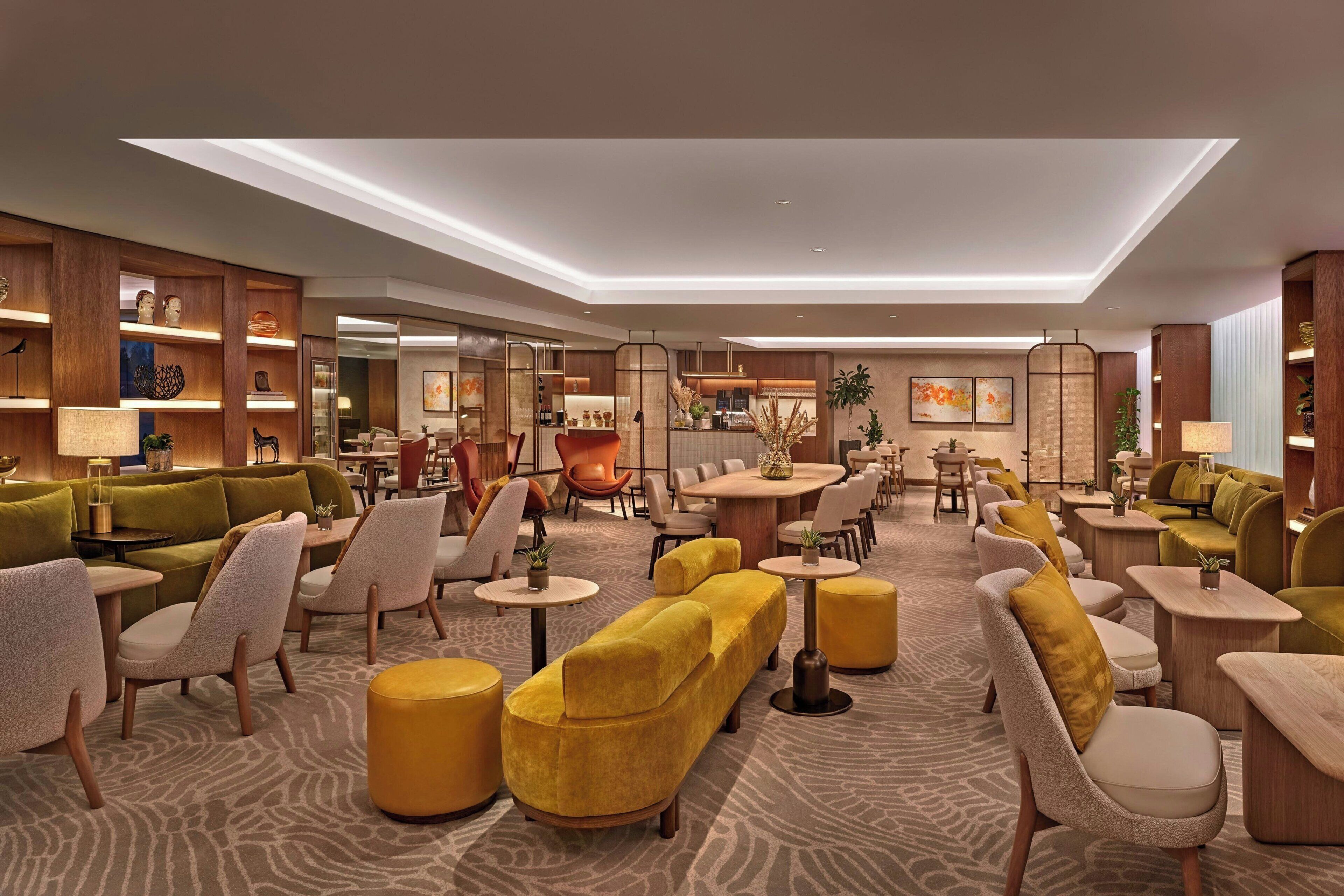 A spacious lobby with a mix of seating areas, including sofas and chairs, and a central dining table surrounded by chairs.