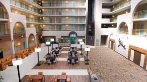 Een hotelentree met meerdere niveaus, zitgedeeltes, tafels en een centrale trap.