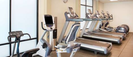 Un gimnasio con varias cintas de correr y una máquina elíptica.