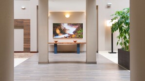 Een hal met een houten bank, een grote flatscreen televisie aan de muur en een potplant.