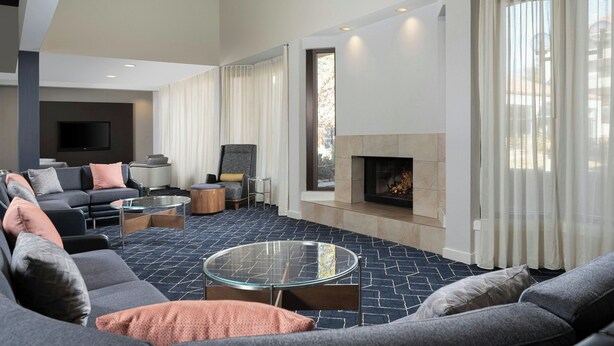 A modern living room with a fireplace, comfortable seating, and a flat-screen TV.