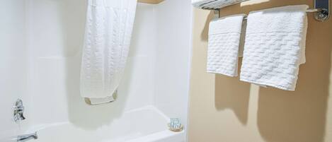 A bathroom with a bathtub, a shower curtain, and a towel rack with towels.