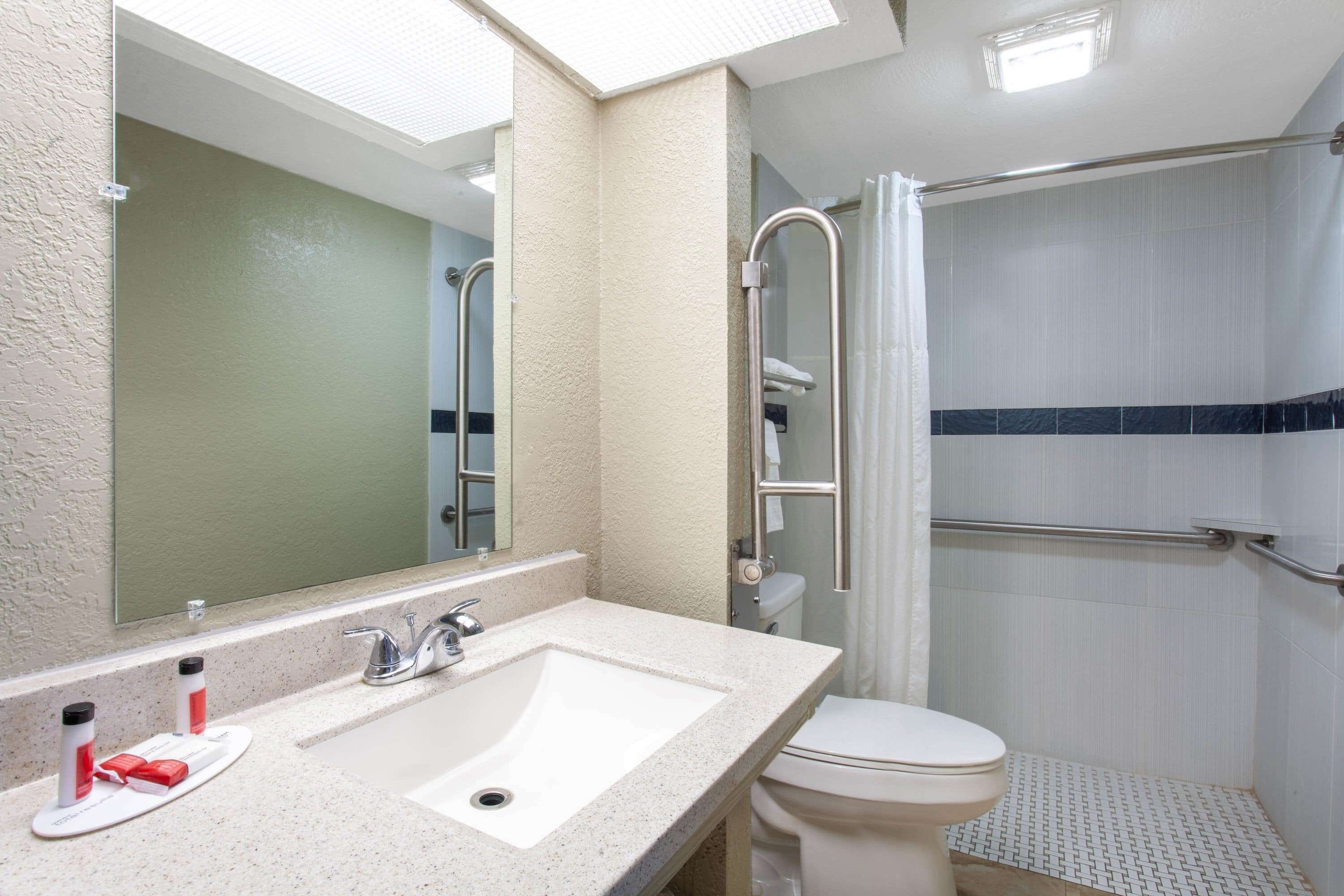 A bathroom with a sink, mirror, toilet, and shower.
