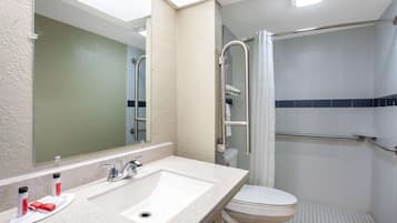 A bathroom with a sink, mirror, toilet, and shower.