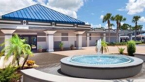 A modern building with a blue roof, a fountain, and palm trees.