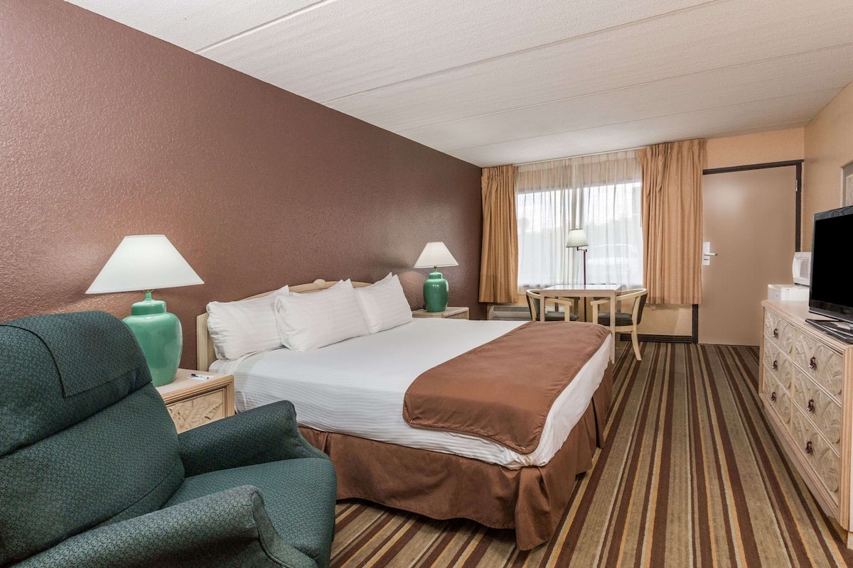 Une chambre d’hôtel avec un grand lit, un bureau, une chaise, une télévision et une commode.
