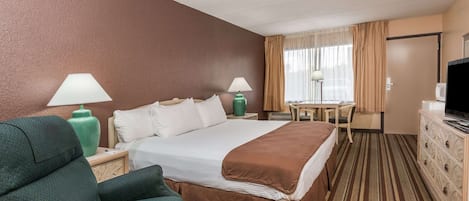 Una habitación de hotel con una cama grande, un escritorio, una silla, un televisor y un aparador.